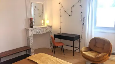a living room with a fireplace and a chair and a table at Chambre Voltaire ou Chambre Beckett, terrasse en bord de Sorgue in Le Thor