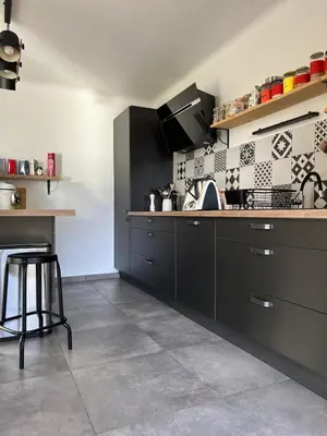 a kitchen with black cabinets and a tile floor at Villa Saint Martin in Malemort-du-Comtat