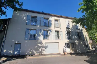 a man standing in front of a white building at Appartement Confortable & Lumineux in Lambesc