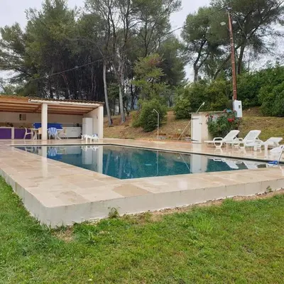 a large swimming pool with chairs and a house at Appartement dans campagne aixoise in Ventabren