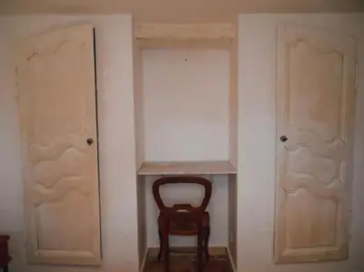 a wooden chair sitting in a room with two doors at Maison de campagne avec Piscine in Pernes-les-Fontaines