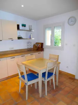 a kitchen with a wooden table and two chairs at Maison de campagne avec Piscine in Pernes-les-Fontaines