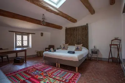 a bedroom with a bed and a piano in a room at Grande maison de charme au coeur de Goult in Goult