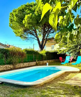 a swimming pool in a yard with two chairs and a tree at Villa la Farigoule in Carpentras