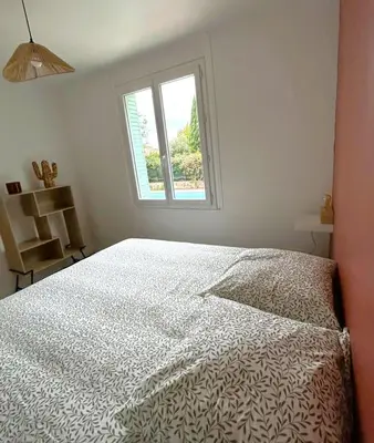 a white bedroom with a bed and a window at Villa la Farigoule in Carpentras
