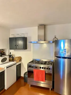 a kitchen with a stainless steel stove and refrigerator at La maison Haut-perché townhouse with view and jacuzzi in Saumane-de-Vaucluse