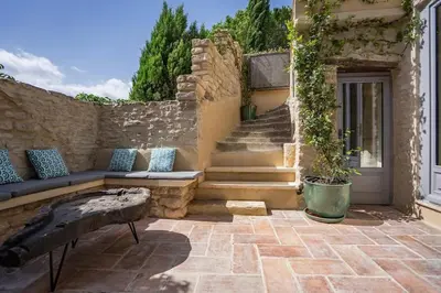 a patio with a bench and stairs with a building at Maison d'exception au cœur de Goult in Goult