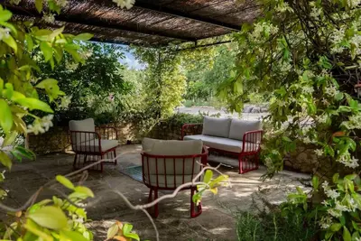 a patio with chairs and a couch under a pergola at Superbe Mas provençal, entre Gordes et Roussillon in Murs