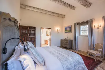 a bedroom with a bed and a chair and a window at La Becasse Heritage Pool Manor in Bonnieux