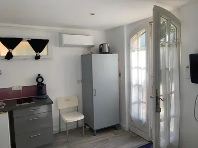 a kitchen with a refrigerator and a table and a chair at Studio indépendant en RDC de villa, parking in Pertuis