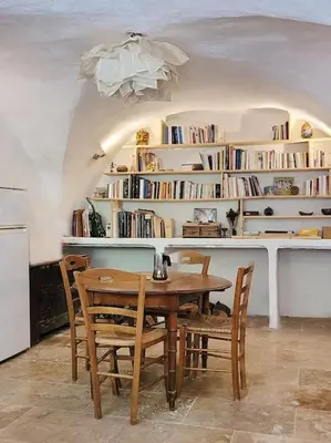 a dining room with a table and chairs and bookshelves at Les voûtes du vieux village in Lauris