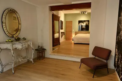 a room with a bed and a mirror and a chair at Suite dans maison d'artiste in LʼIsle-sur-la-Sorgue
