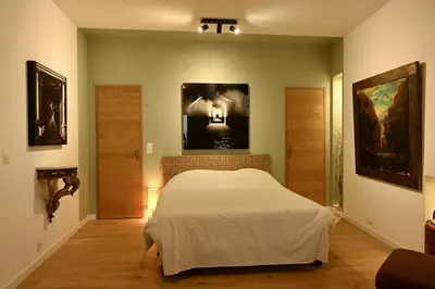 a bedroom with a bed and paintings on the wall at Suite dans maison d'artiste in LʼIsle-sur-la-Sorgue