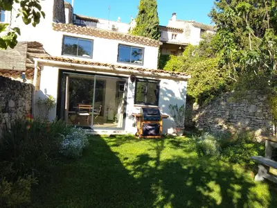 a small white house with a yard with grass at Le Souliadou in Saint-Didier