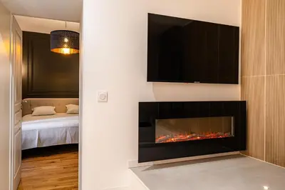 a living room with a fireplace with a tv above it at Suite cosy dans le centre historique in Aix-en-Provence