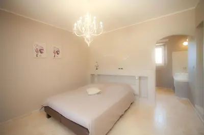 a white bedroom with a bed and a chandelier at La Collina De Rve in Apt