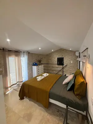 a bedroom with a bed and a brick wall at Charmante maison Provençale avec grand jardin in LʼIsle-sur-la-Sorgue