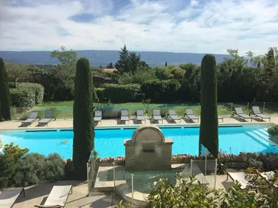 a large swimming pool with chairs and trees at Le balcon de Gordes in Gordes