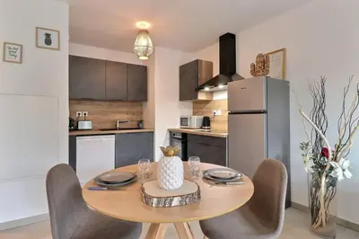 a kitchen with a table with chairs and a refrigerator at Appartement moderne - Terrasse - Piscine - Parking in Ventabren