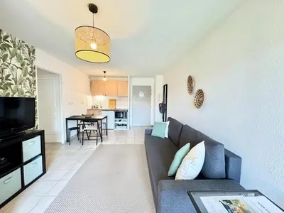 a living room with a couch and a kitchen at Jungle Cosy - Gare - Bus - Parking gratuit - WIFI in Avignon