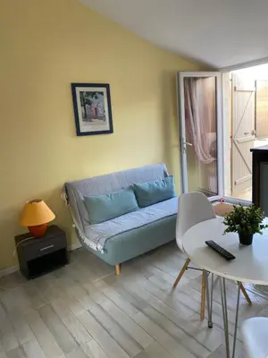 a living room with a blue couch and a table at Studio à la campagne in La Tour-dʼAigues