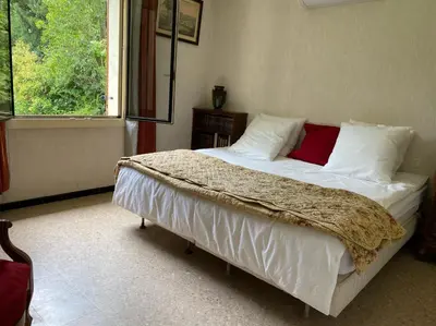 a bedroom with a bed with white sheets and red pillows at Villa 10 mins a pieds du centre de L Isle sur la Sorgue in LʼIsle-sur-la-Sorgue