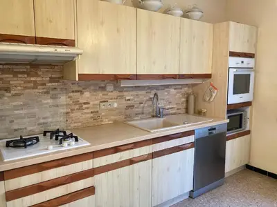 a kitchen with wooden cabinets and a sink at Villa 10 mins a pieds du centre de L Isle sur la Sorgue in LʼIsle-sur-la-Sorgue