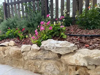 a garden with rocks and flowers in front of a fence at STUDIO campagne Les Clapiers AIX EN PROVENCE in Aix-en-Provence