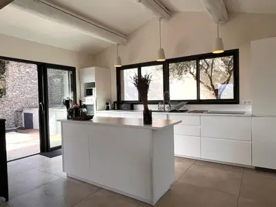a kitchen with white cabinets and a large window at La Calade de Goult in Goult