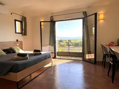 a bedroom with a bed and a balcony with a view at La Calade de Goult in Goult
