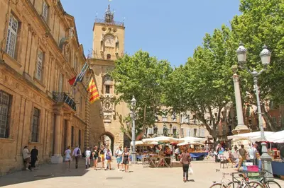a group of people walking down a street with a clock tower at Chez Florence - Appartement T2 d au cœur du centre ville historique - Proche Cardeurs et Mairie in Aix-en-Provence