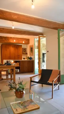 a living room with a table and a kitchen at La Piscine dans la Foret in Gordes