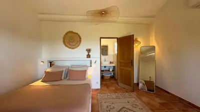 a bedroom with a bed and a bathroom with a sink at La canopée, Bastide sur les hauteurs de Lourmarin in Lourmarin