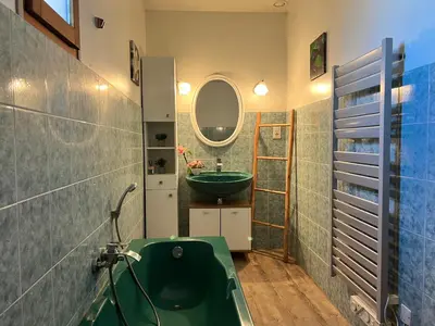 a bathroom with a green tub and a sink at Domaine Les feuilles de Chêne in Carpentras