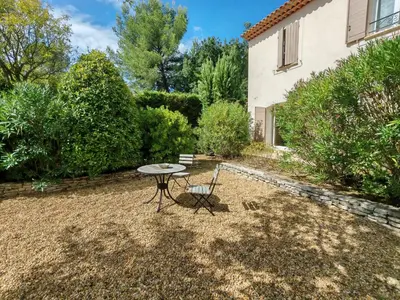 a patio with a table and a chair in a yard at La bastide le Jucamas in Saint-Saturnin-les-Apt