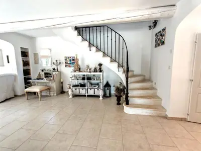 a staircase in a living room with white walls and tile floors at La bastide le Jucamas in Saint-Saturnin-les-Apt