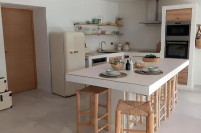 a kitchen with a large white island with stools at Appartement Indépendant avec Jardin et Piscine en Provence in Ventabren