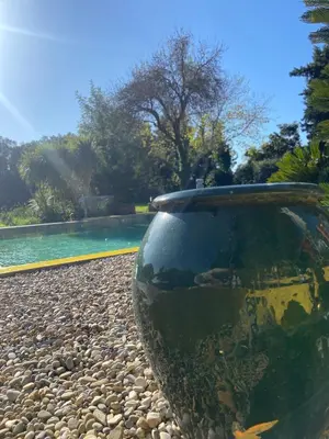 a vase sitting on the ground next to a pool at La Villa Astra de 4 à 12 personnes - Domaine Astra, Grans in Grans