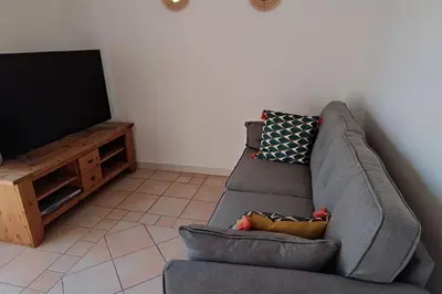 a living room with a couch and a television at Escapade en maisonnette indépendante avec piscine in Châteaurenard