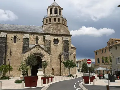 an old brick church with a tower on a street at Maison provençale, piscine, calme et Lubéron in Le Thor