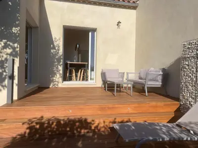 a patio with chairs and a table on a wooden deck at logement avec jacuzzi in Joucas