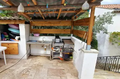 an outdoor kitchen with a wooden pergola at Villa Provençale Harmonie 8 Guest poolhouse in Lambesc