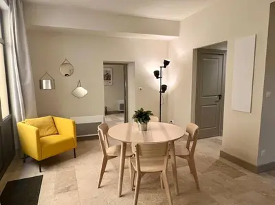 a dining room with a table and a yellow chair at Appartement au coeur du centre historique in Aix-en-Provence