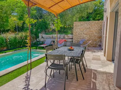 a patio with a table and chairs next to a pool at Villa Lisette, un meublé de tourisme 3 étoiles au cœur de Goult in Goult