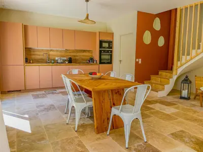 a kitchen with a wooden table and white chairs at Villa Lisette, un meublé de tourisme 3 étoiles au cœur de Goult in Goult