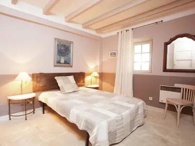 a bedroom with a bed and a table and a window at Cottage in Oppède with Pool and Garden in Maubec