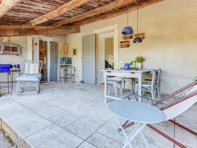 a patio with a table and chairs on it at Charming Cottage in Oppède amidst Vineyards in Maubec