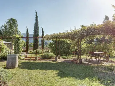 a garden with a pergola and a table and chairs at Cottage in Oppède with Poolside Bliss in Maubec