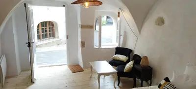 a living room with a table and chairs and an open door at Les studettes du Beffroi in Cucuron