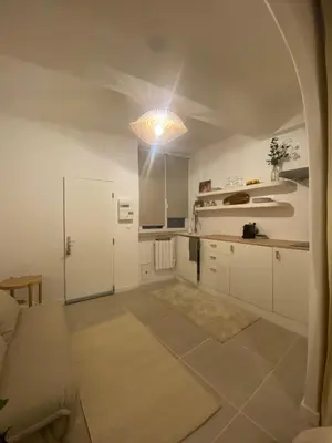 a kitchen with white cabinets and a light at Studio charmant hyper centre in Aix-en-Provence